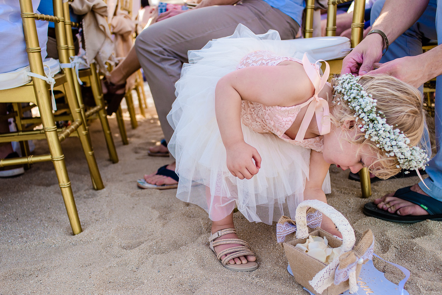 Flower girl playing with the sand during the beach wedding ceremony in Los Cabos