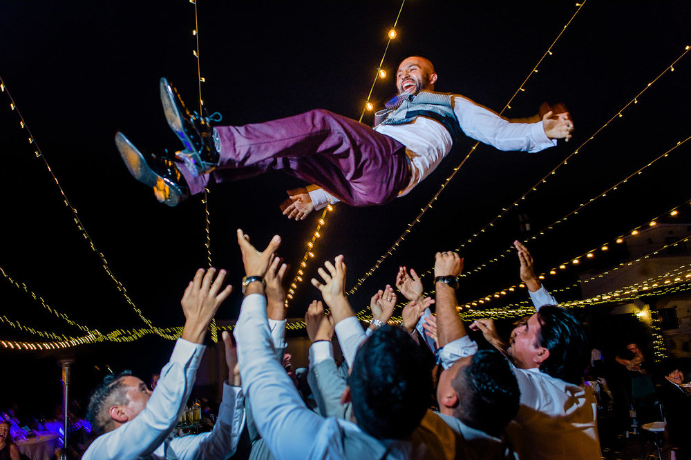 Groom thrown in air by his best friends and groomsmen. Funny moments of a Cabo wedding