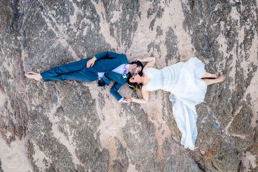 Aerial shoot of bride and groom kissing on the rocks during their wedding day at Fiesta Americana Los Cabos