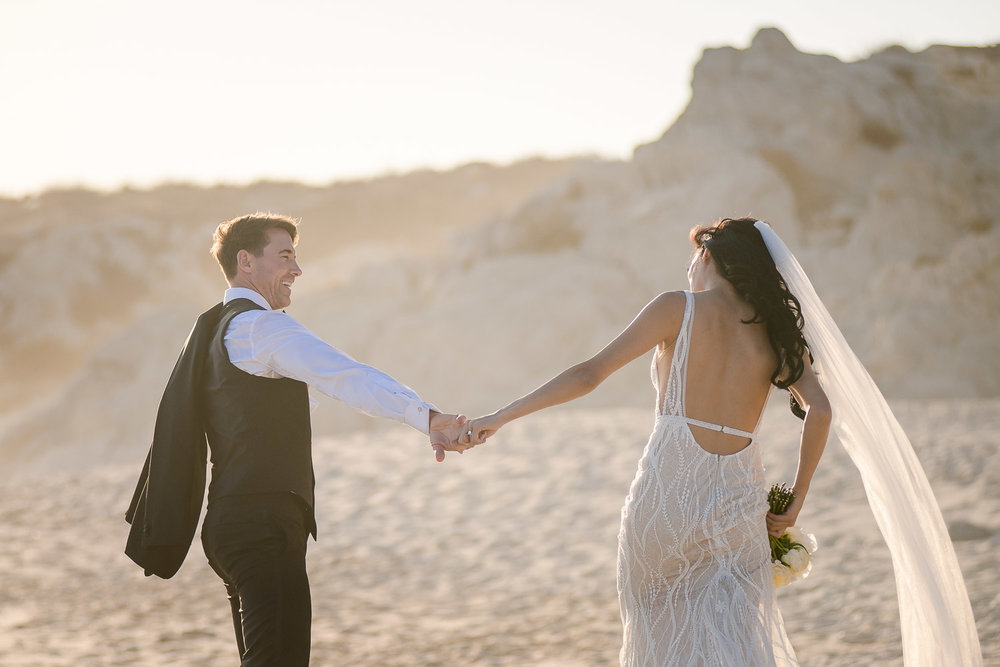 bride and groom walking on the beach during their photo session right after the ceremony