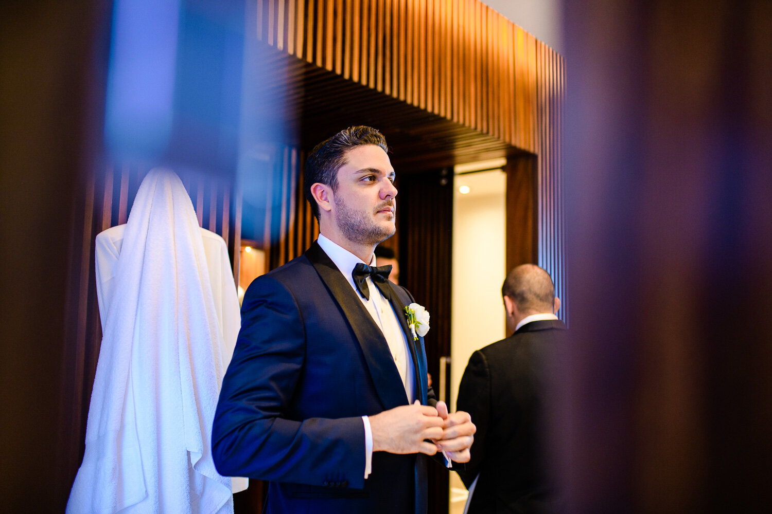 groom getting ready in front of the mirror, fixing his jacket