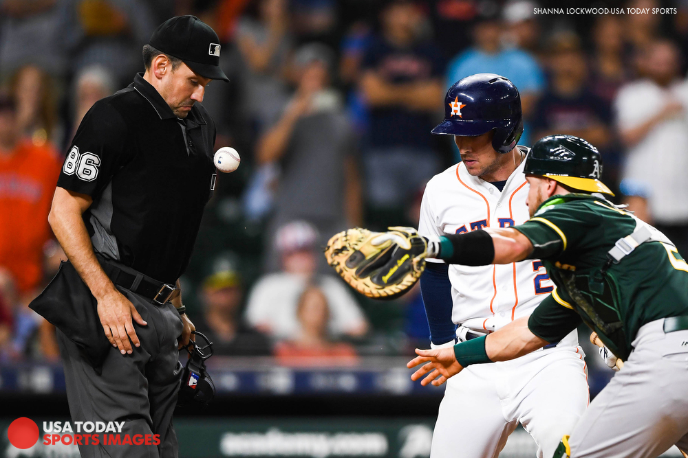  Jul 10, 2018; Houston, TX, USA; The baseball bounces off the chest of umpire David Rackley (86) as Oakland Athletics catcher Jonathan Lucroy (21) tries to tag out Houston Astros third baseman Alex Bregman (2) at home plate during the eleventh inning