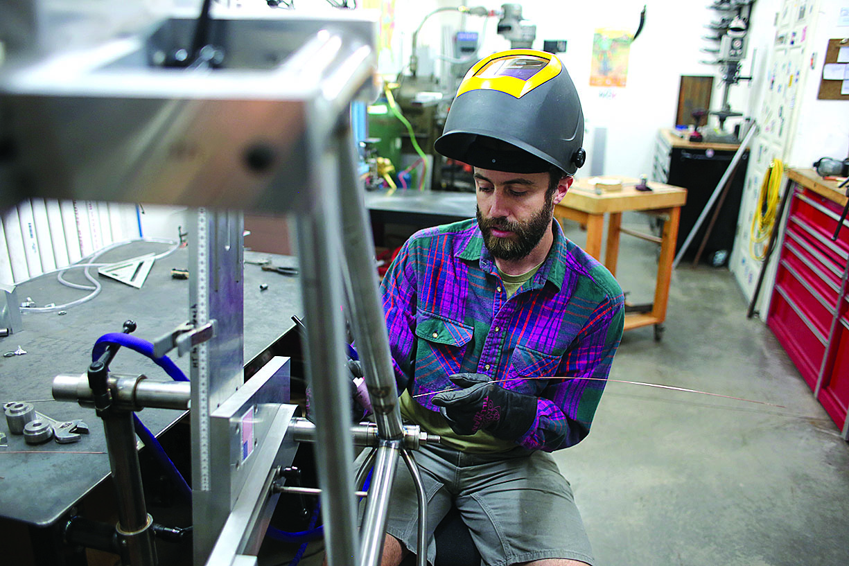 Eric Tomczak welds a frame in his shop. He works in steel for its longevity, versatility and absorption./Photo by Jennaye Derge