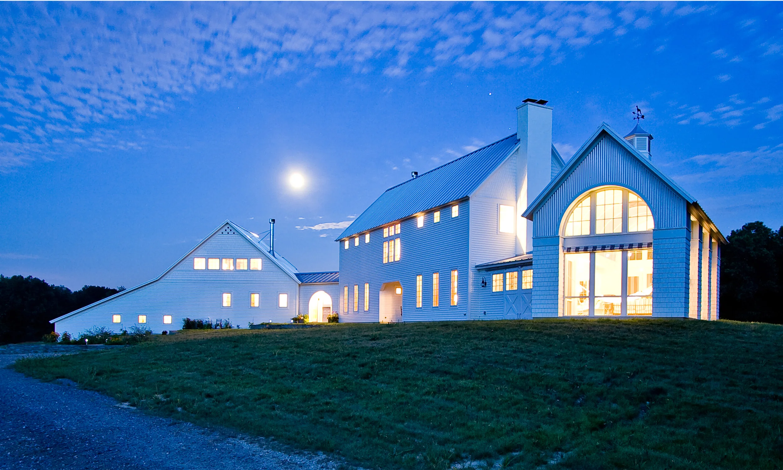Firefly Hill is a new home in the vineyard region of southwest Michigan. The site includes five acres of meadow and twenty acres of conservancy-protected woodland. The project has been featured in Beautiful Homes magazine, Shore magazine, and has been honored with a 2009 Design Award of Merit from the Association of Licensed Architects. The home contains 3,500 sq. ft. of interior space, and is of wood-frame construction clad in sustainably-harvested cedar clapboard siding and shingles. Other green features include passive solar, geothermal heating and coolding, salvaged materials, EnergyStar appliances and equipment, and radiant floors throughout. The exterior was inspired by the vernacular farm structures of the Midwest, and the white connected farmsteads of New England evoked in the 19th century children’s cadence, “Big house, little house, back house, barn."