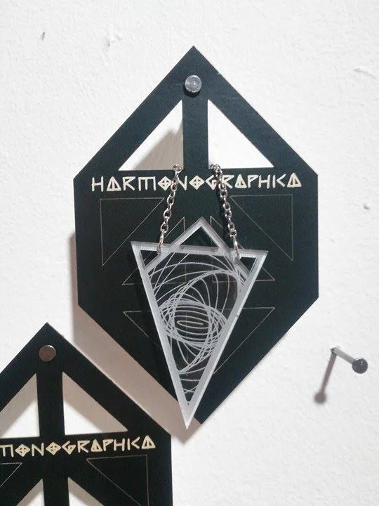 Necklace created using drawings from the Harmonograph. Made from laser engraved clear acrylic. Card packaging also laser engraved and lasercut to mimic the table shape of the Harmonongraph machine.