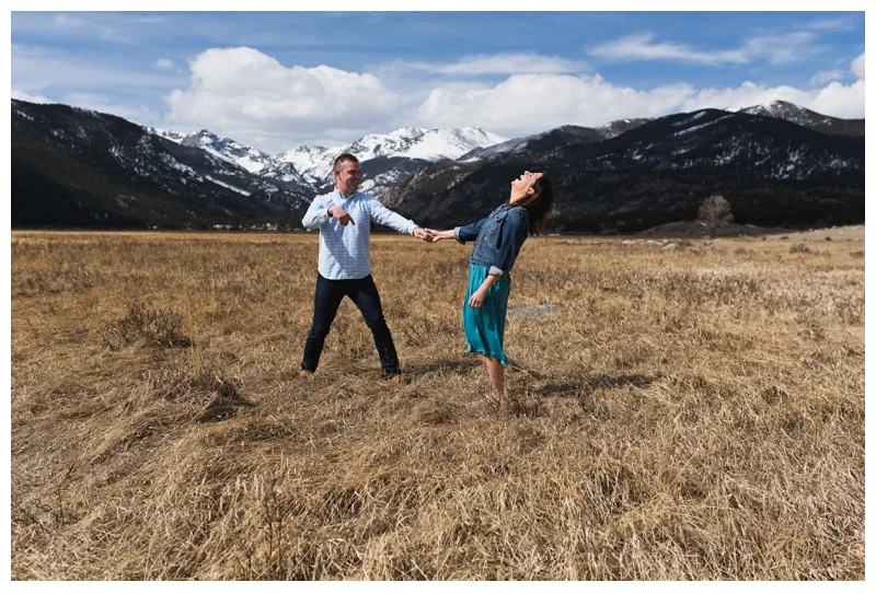 A happily engaged couple laughs at Sprague Lake in Rocky Mountain National Park in Colorado. Engagement photography by Sonja Salzburg of Sonja K Photography.&nbsp;