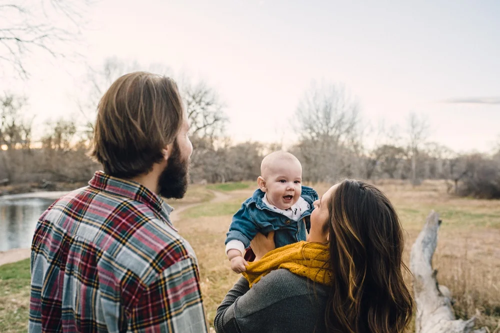 A beautiful baby and her family at Legacy Park in Fort Collins, Colorado on a warm late fall evening. Family portrait photography by Sonja Salzburg of Sonja K Photography.&nbsp;