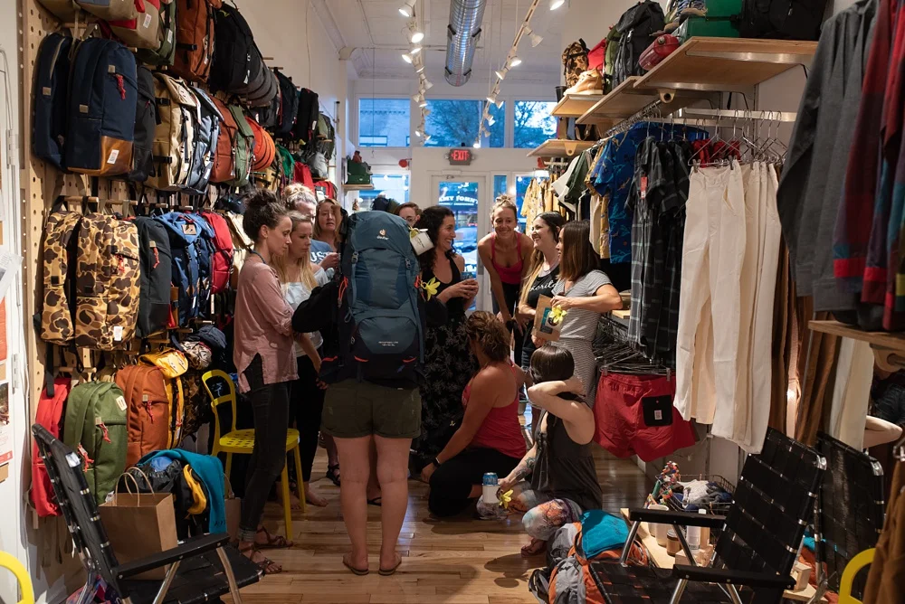 A packing party at the Wellbody Woman Summer TRIBE Program at Topo Designs in Old Town Fort Collins, Colorado. Corporate event photography by Sonja Salzburg of Sonja K Photography.&nbsp;