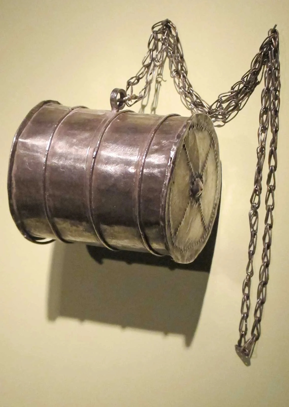 Barrel-shaped pendant by Mende artist, Sierra Leone, of metal, early 20th century.