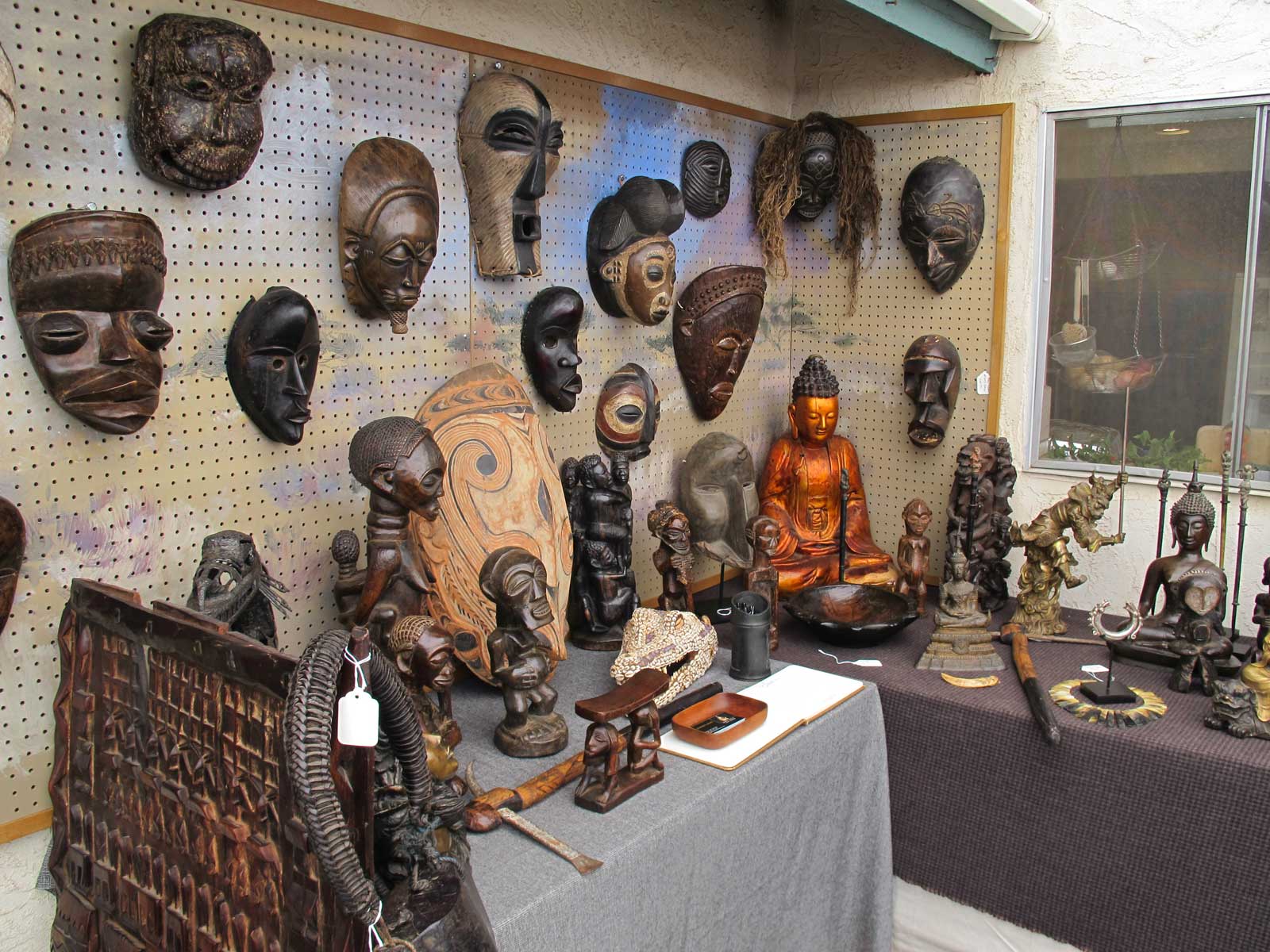 A variety of African masks, buddhist art and other sculpture in the collection of Geoffrey Logan.