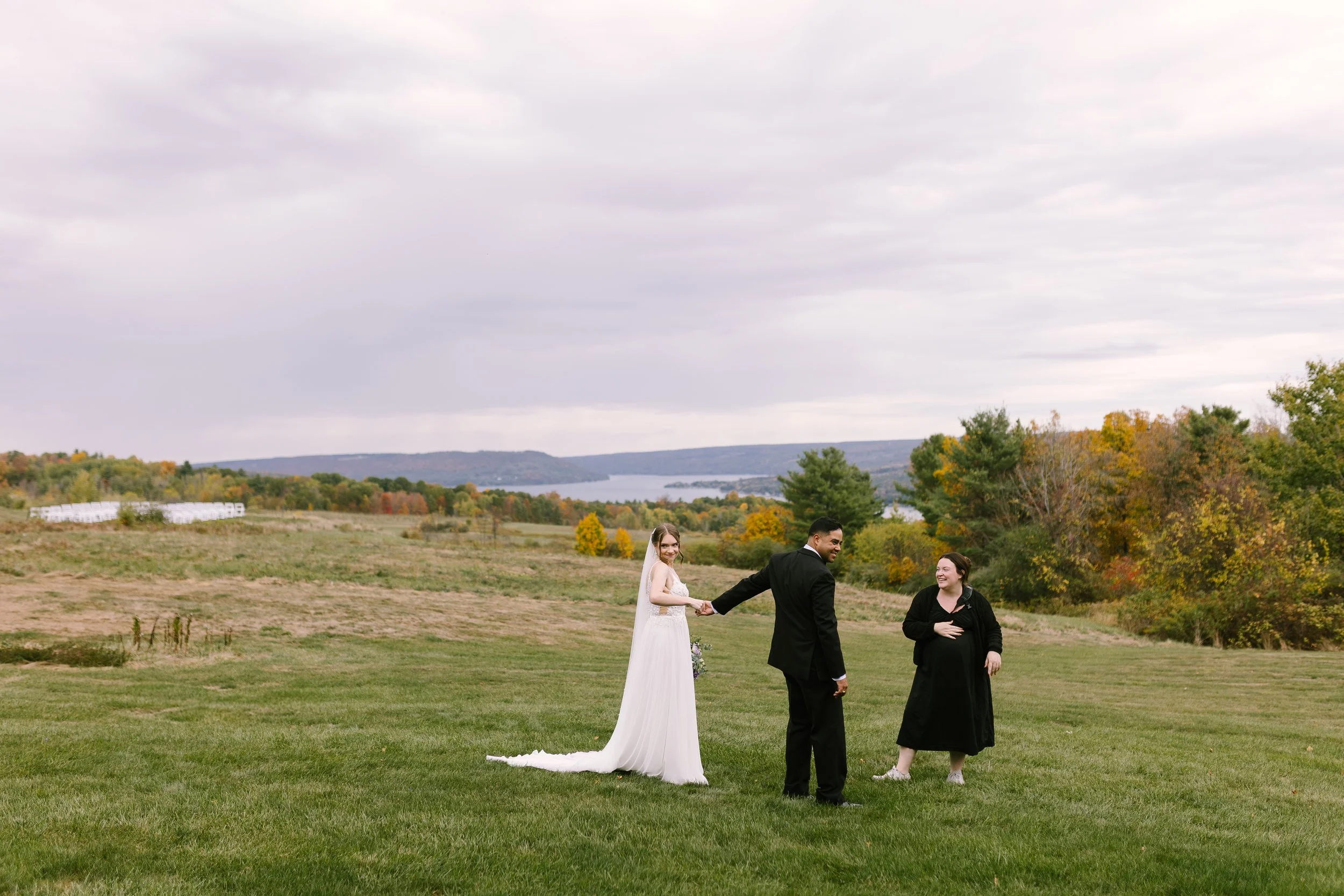 Candid of wedding photographer laughing with bride and groom at Manor House Estate