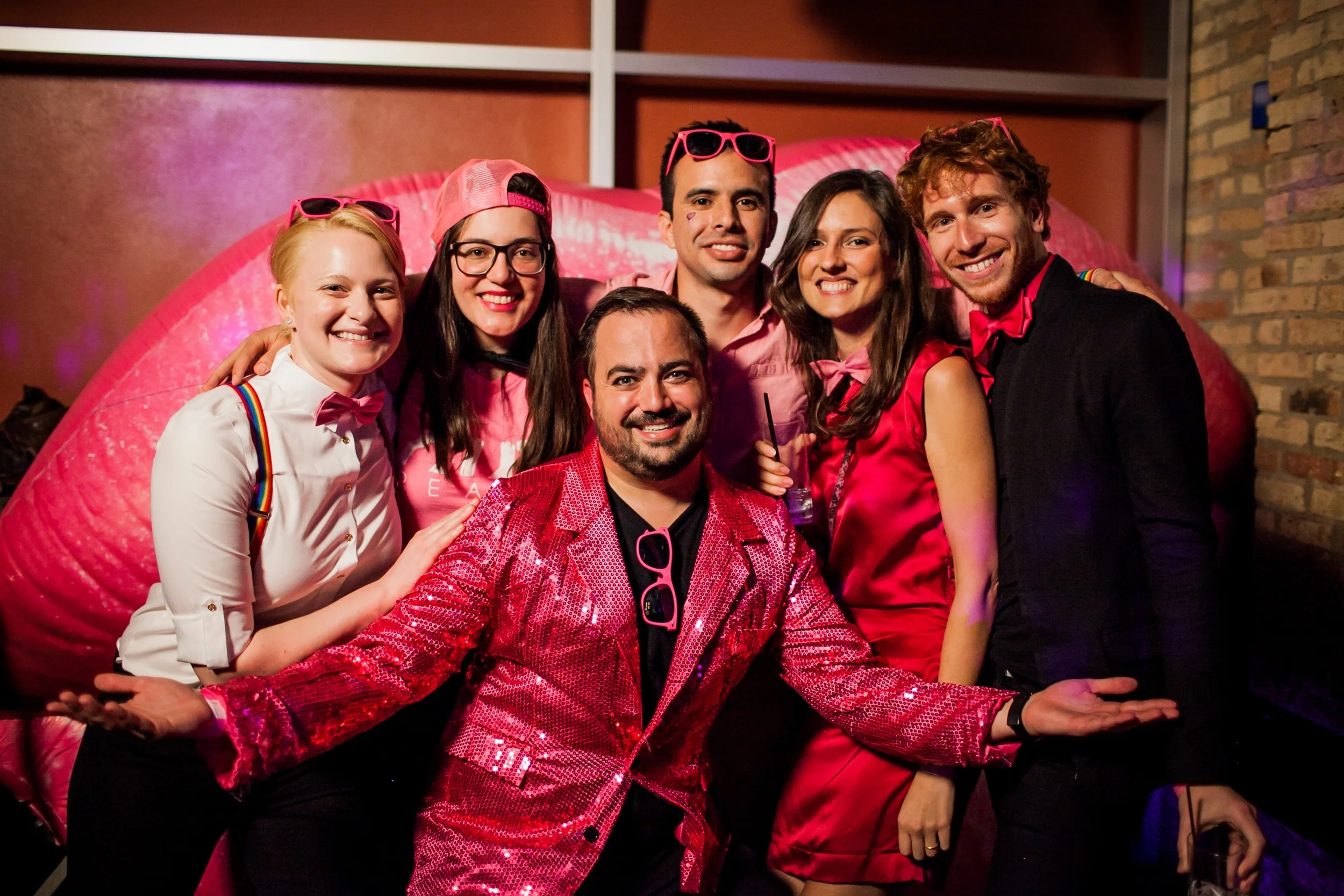Booth OUTreach co-chair and project leader, Erik Underwood (center), strikes a pose with his fellow co-chairs in front of the signature pink lips at OUTreach's annual #PinkParty at Sidetrack Video Bar in Boystown.