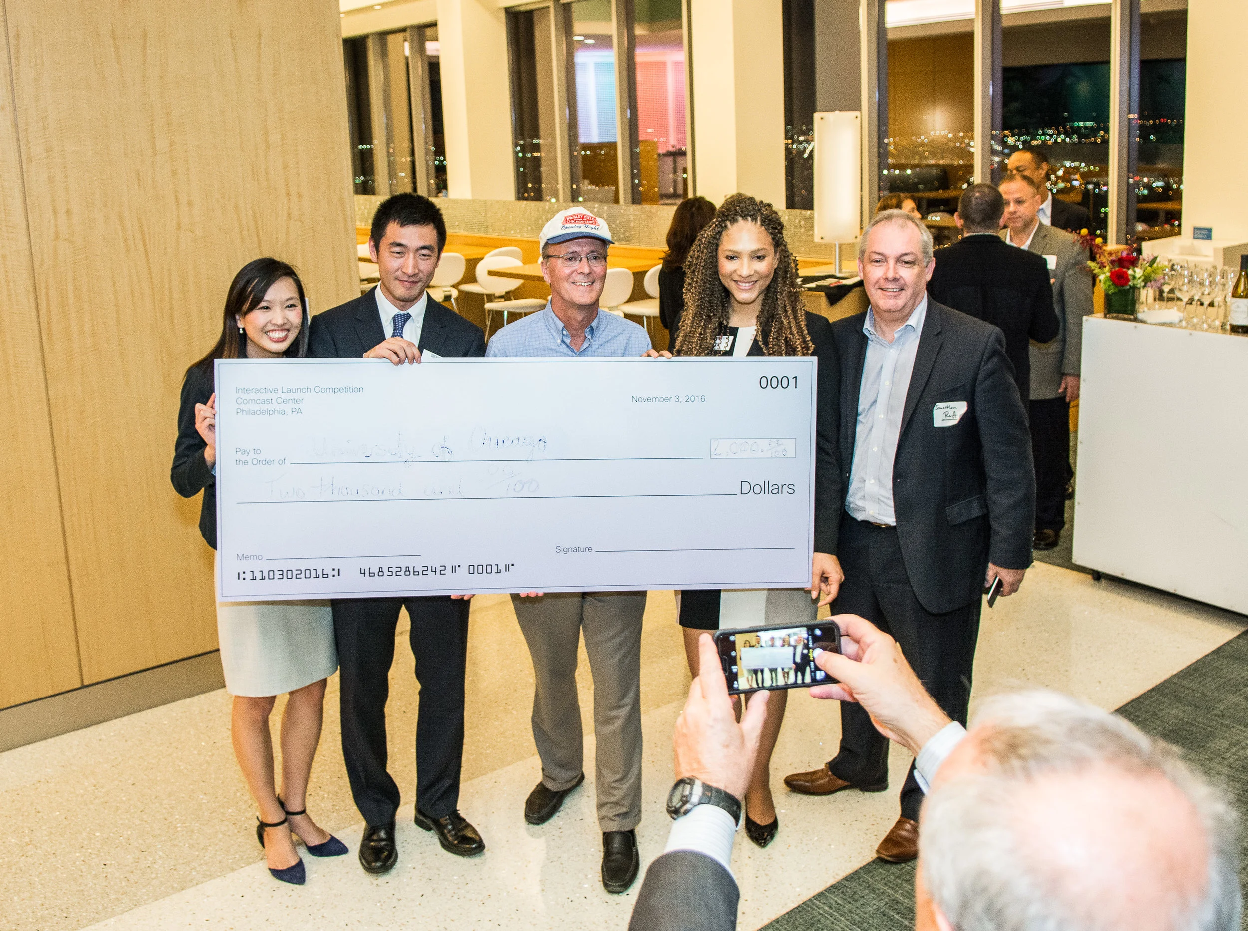 Vivian Fan 17', Ray Lui 17', and Alexis Miller 17' pose holding the team’s 1st place cash prize with Interactive TV Works Case Competition Organizer Craig Leddy and Arris’ coach Jonathan Ruff.