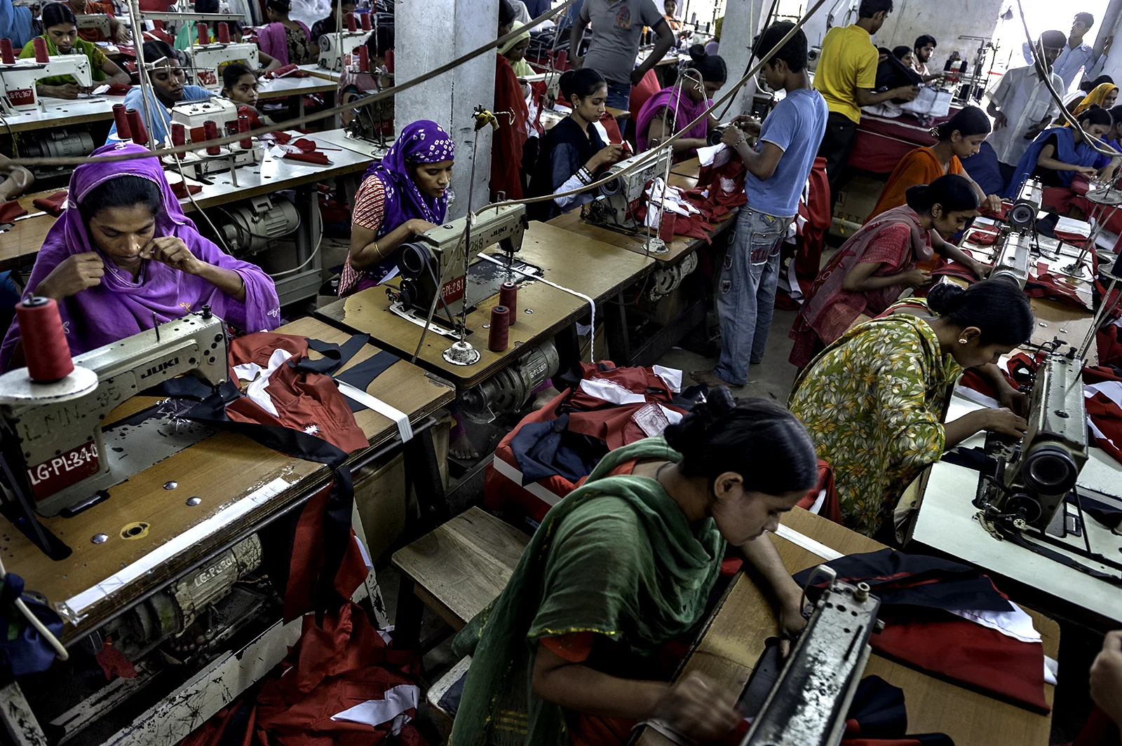 Mumtaz Hassanullah, 32 (far left, in purple), cuts thread with her teeth as she sews continuously in one of Bangladesh's many garment factories. It is a job she does from 8 A.M. to 8 P.M. nearly every day. These are long hours in an often hot enviro