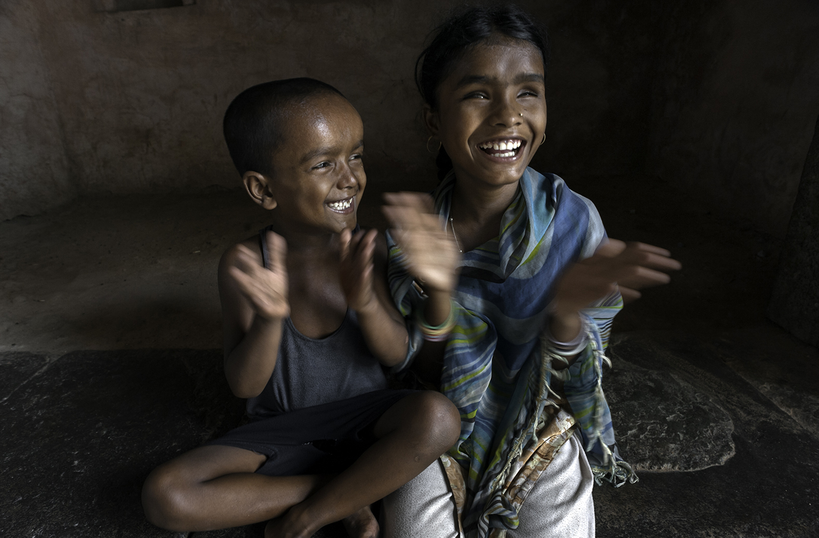Hunupa Begum and her brother Hajimudin Sheikh, 6 resort to singing and clapping their hands to play and in the process make each other laugh. © Renée C. Byer