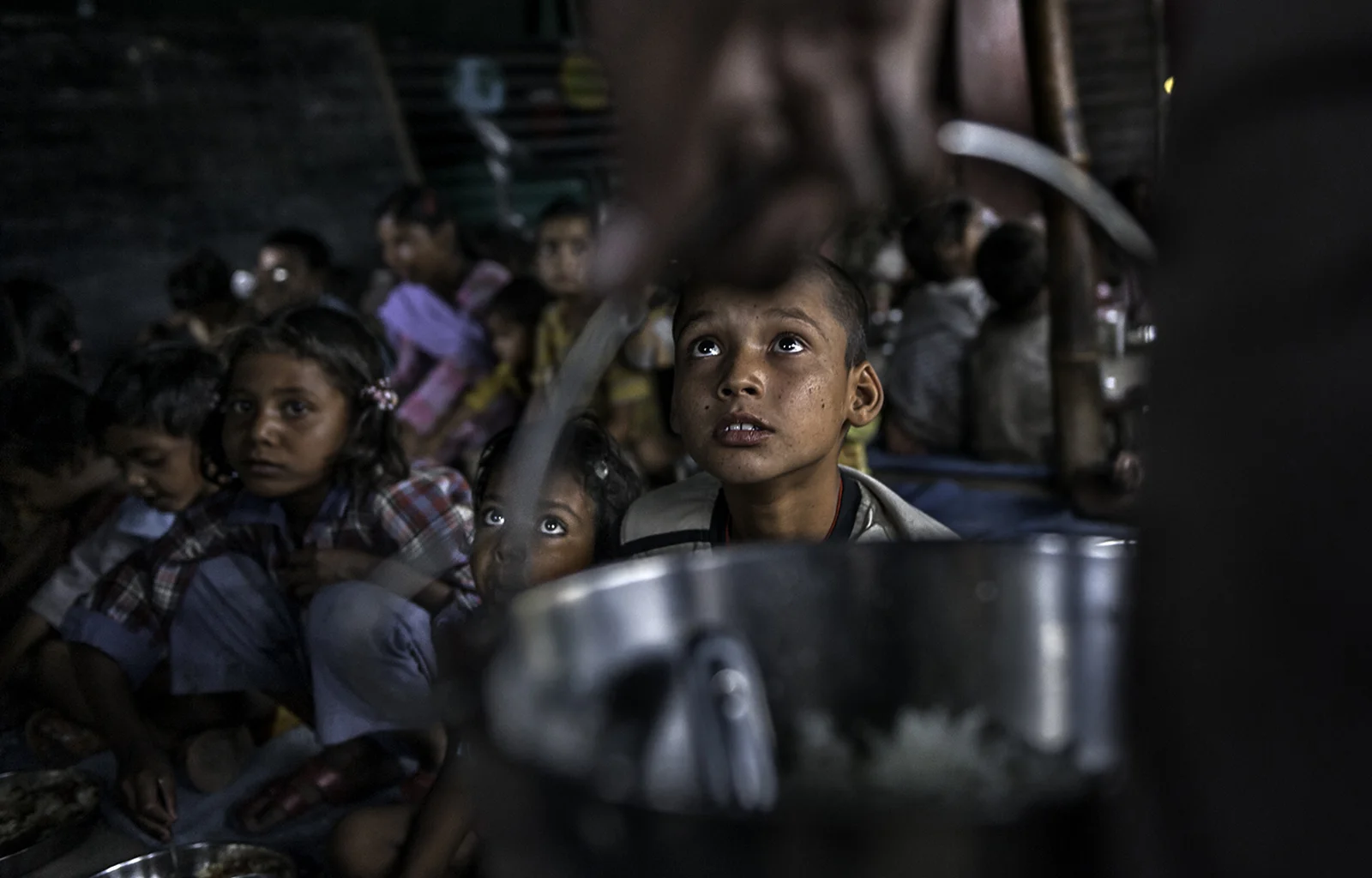 Suraj, 10, waits as rice is passed out in a tent school at the Charan Slum Settlement funded by the Tong-Len Charitable Trust. © Renée C. Byer