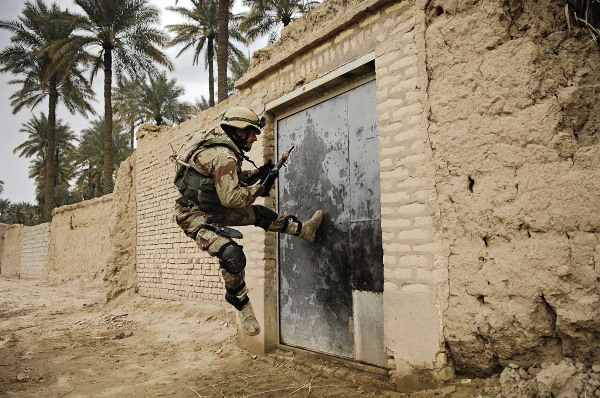 An Iraqi army soldier tries to kick open a gate during a cordon and search for insurgence and weapons caches in Chubinait, Iraq. 2007 © Stacy L. Pearsall