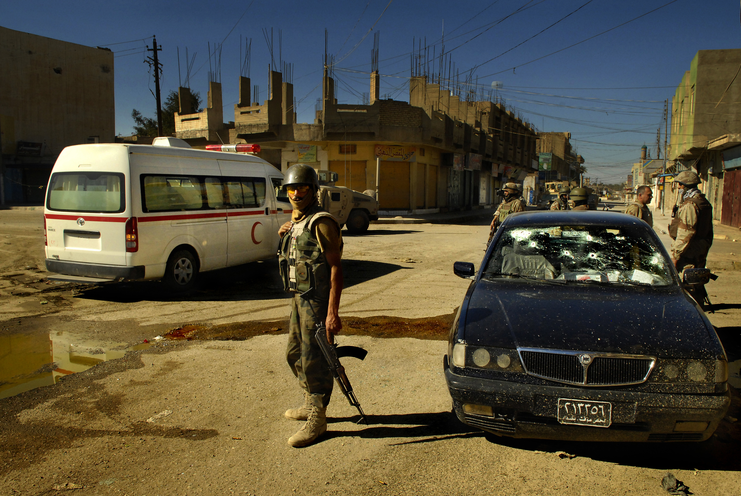 After shooting a fleeing insurgent's vehicle, members of the Iraqi army, 4th Battalion, 2nd Brigade, 5th Division, provide medical assistance to the car's occupants during an operation in Old Baqubah, Iraq. 2007 © Stacy L. Pearsall