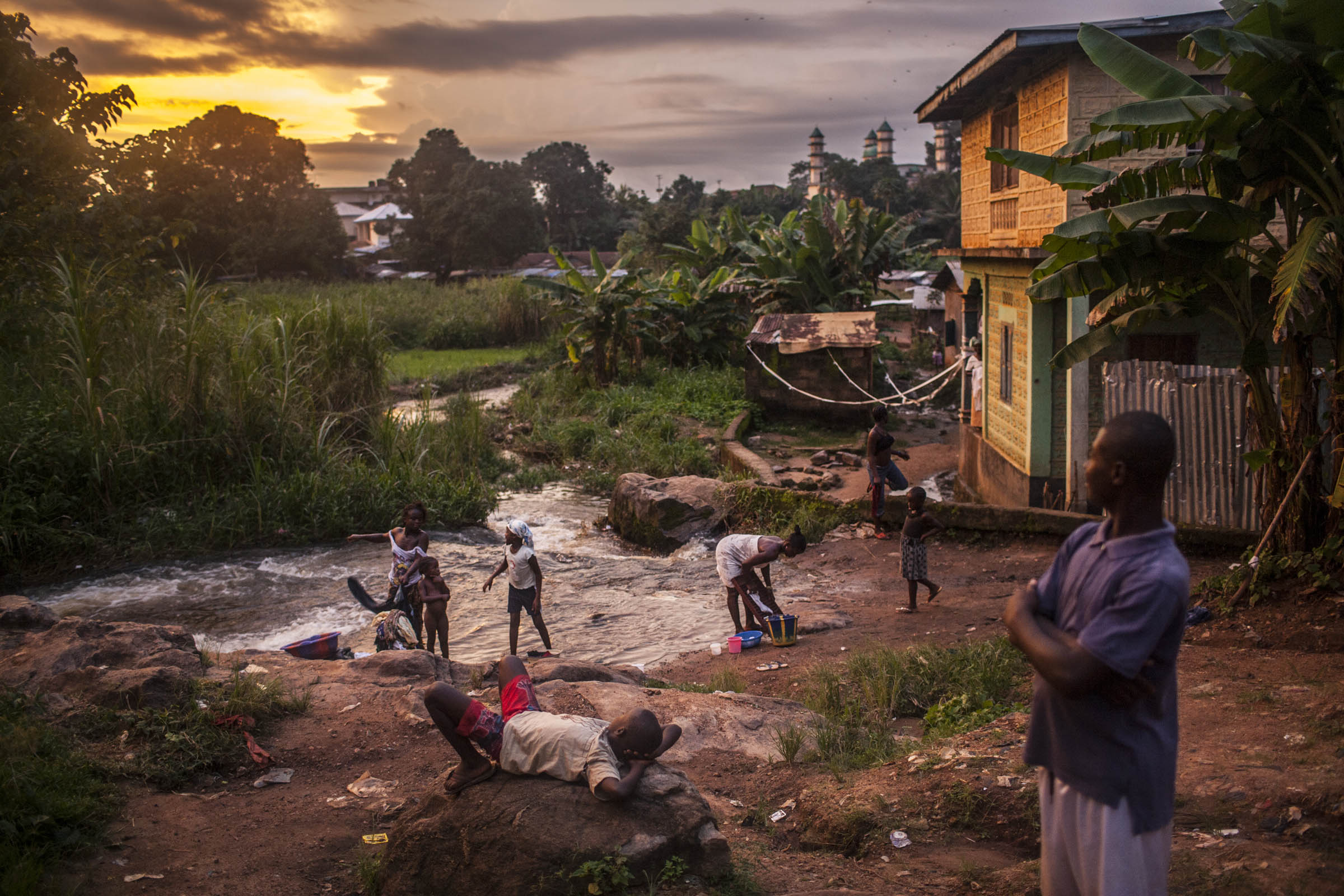 Residents of the town of Kailahun gather along a river at dusk on Tuesday, August 19, 2014. Kailahun district, in eastern Sierra Leone, has been most heavy affected by the ongoing Ebola outbreak. © Pete Muller/Prime for the Washington Post