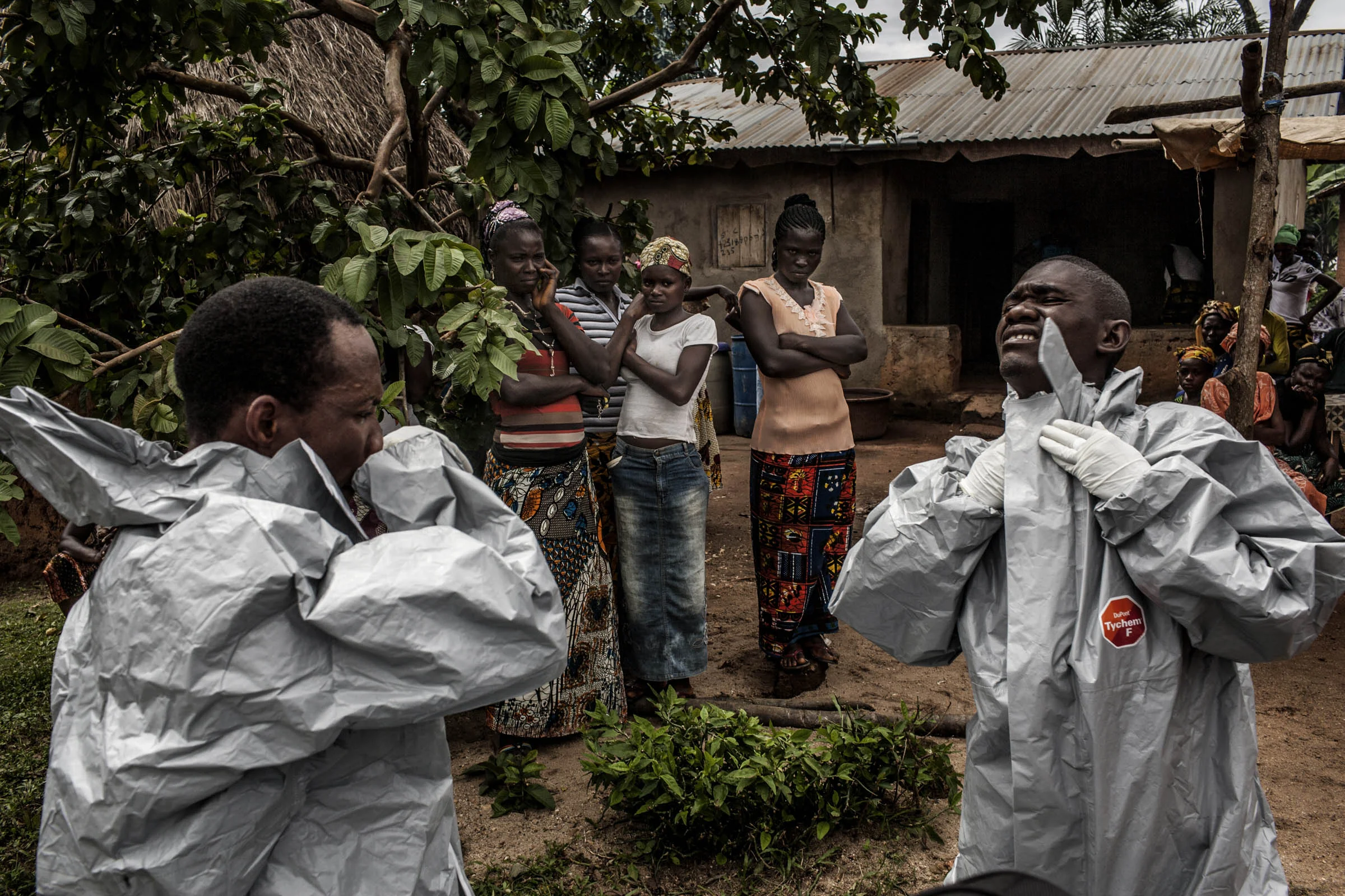 Members of a Red Cross burial team put on personal protective equipment before entering the home of a woman suspected of dying of Ebola in the village of Dia on Monday, August 18, 2014. So-called "safe burials," conducted by the International Federation of the Red Cross, are conducted in accordance with rigorous safety procedures. The dead bodies of Ebola victims are extremely infectious. © Pete Muller/Prime for the Washington Post