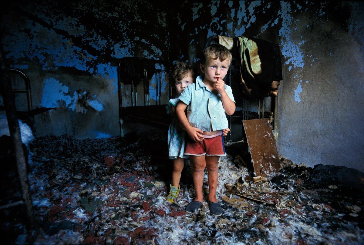 Chechen brother and sister peer from the room in their house which was bombed by Russian troops 1997 © Joe McNally