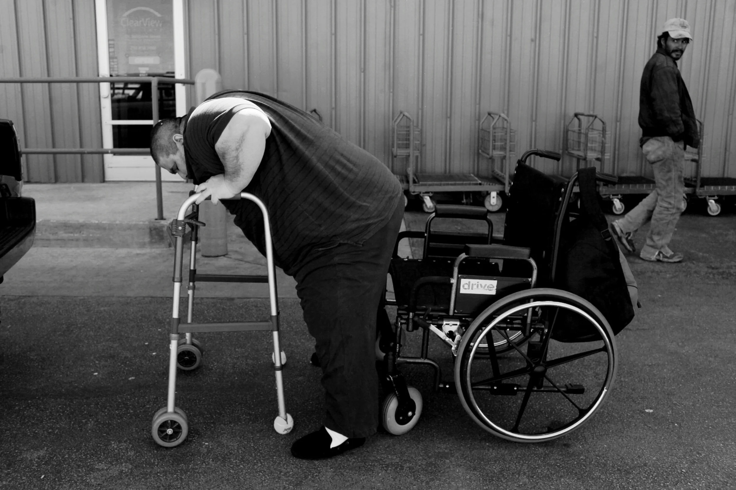Hector Garcia Jr. pulls himself out of his wheelchair and then has to lean on a walker to get into the back seat of his mother's vehicle. © Lisa Krantz/San Antonio Express-News/ZUMA Press