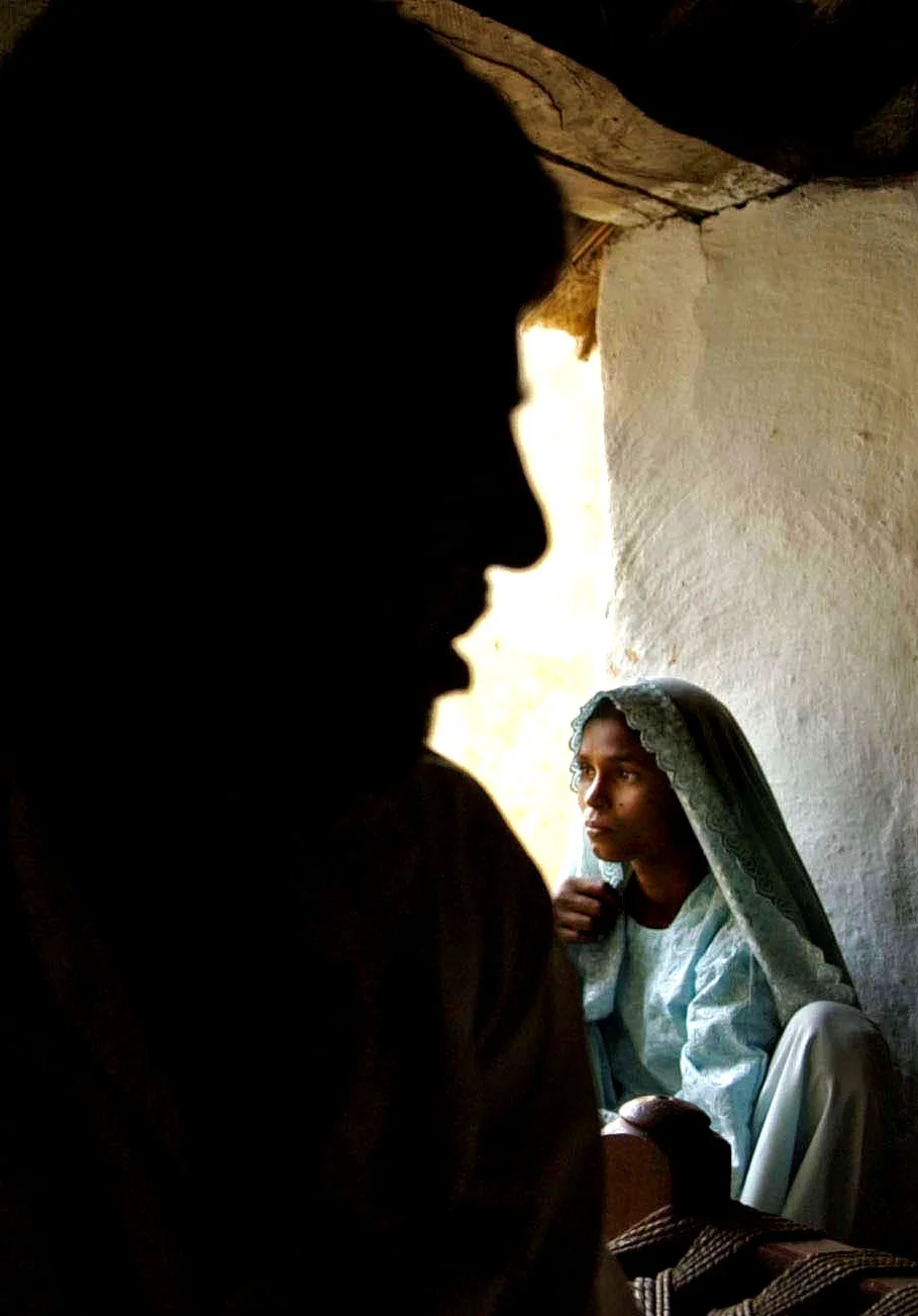 India’s Lost Daughters: Rakshana Begum, right, squats in a corner of her house in the shadow of her husband. © Mary F. Calvert/The Washington Times/ ZUMAPRESS.com