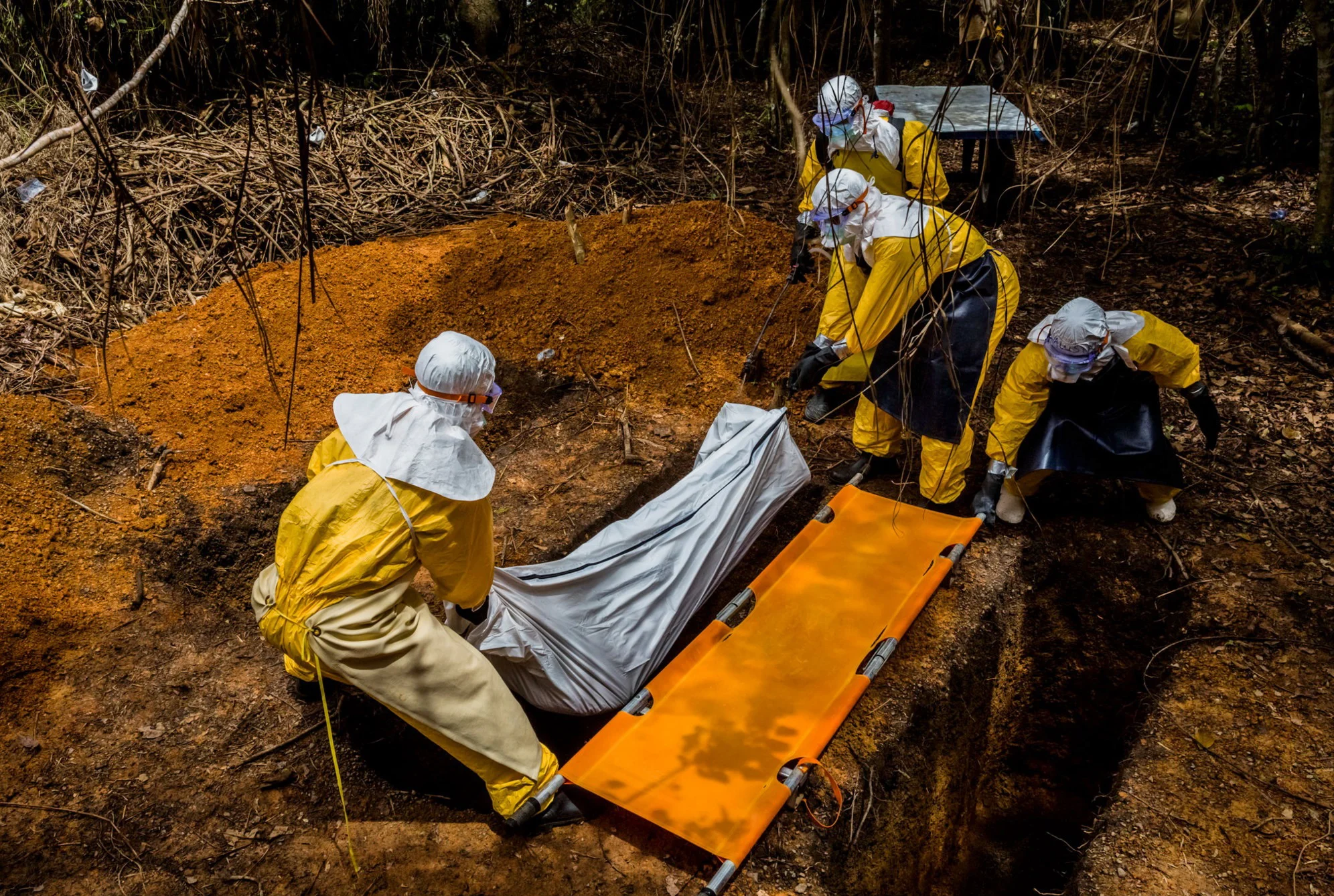 A burial team transfer Ballah Kollie, 20, who lost his fight against Ebola yesterday, into his resting place in a graveyard adjacent to the Bong County Ebola Treatment Unit in Suakoko near Gbarnga in Bong County, Liberia. October 6, 2014 © Daniel Berehulak for The New York Times