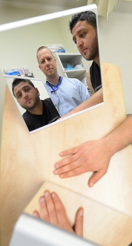 Ashoor Luka used a Mirror Box to cure the chronic pain in his broken wrist with the help of physiotherapist Roland Fletcher (centre). Photo: Boaz Joseph, Surrey Leader. 
