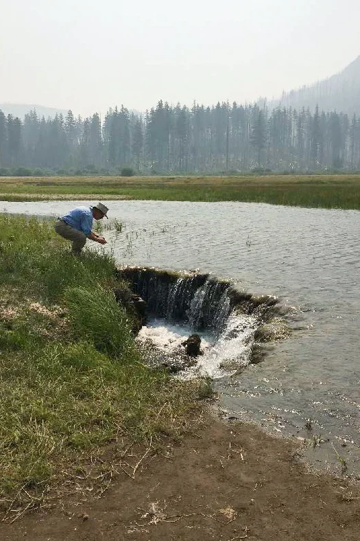 GSOC member Charlie Montross observes water draining from Lost Lake. Note the hazy background created by the forest fires in the Mt. Jefferson area.