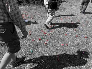 Shotgun shells (in color) littering quarry floor (black-and-white).