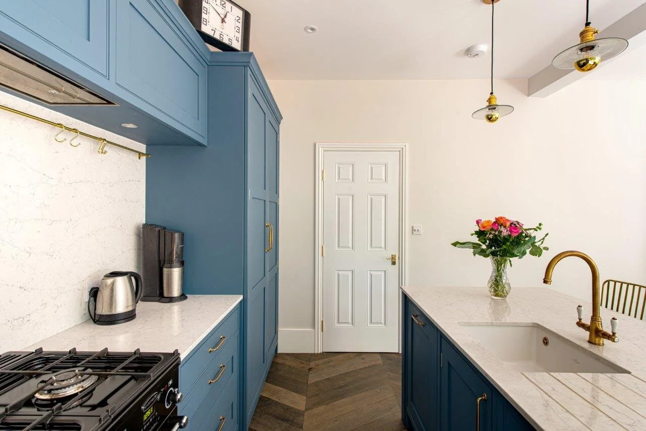 Blue kitchen with range cooker, white quartz worktop with engraved draining grooves and brass tap