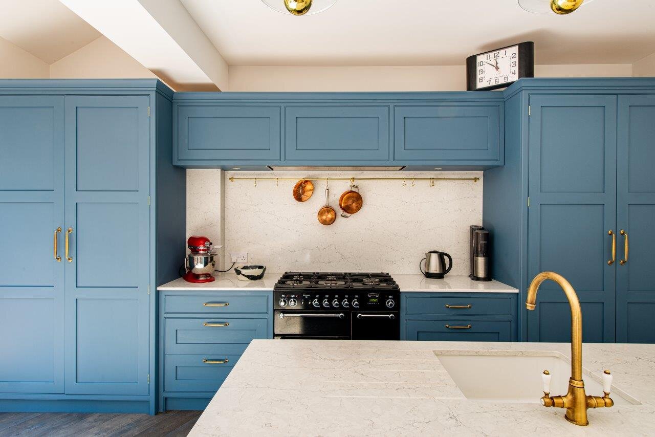 Blue kitchen with brass handles and matching tap.