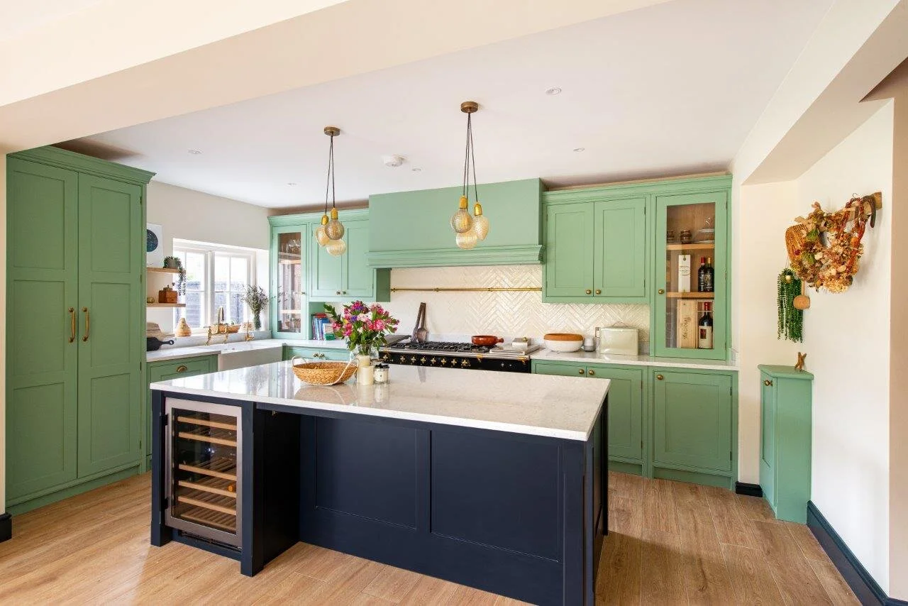 Pale green kitchen cabinetry and black kitchen island with integrated wine cooler fridge.