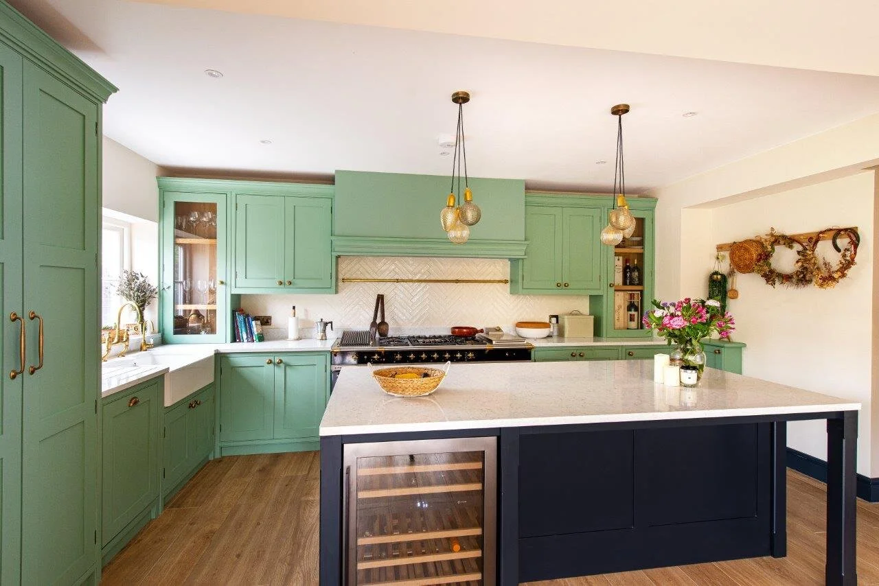 White quartz worktops on pale green kitchen cabinetry and black island.