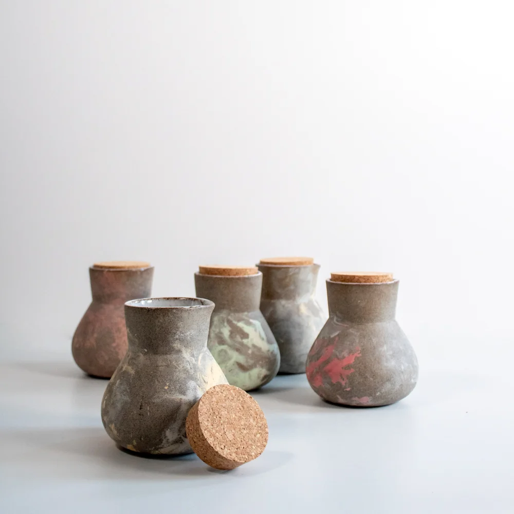The jugs match the cups with their mixed pastel colours on rough grey clay.