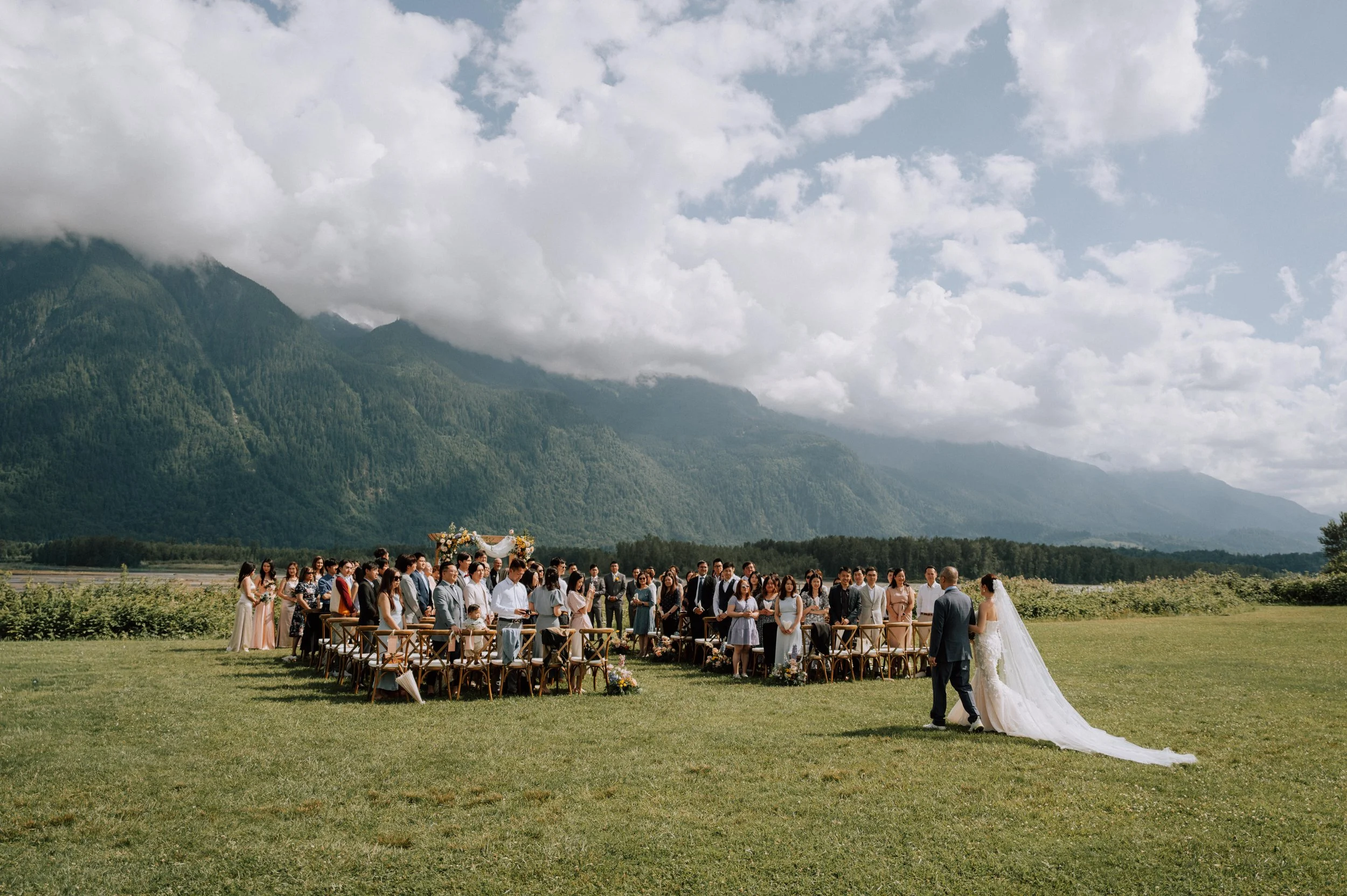 Bride walking down the aisle during an outdoor wedding ceremony at Fraser River Lodge in Agassiz, British Columbia.