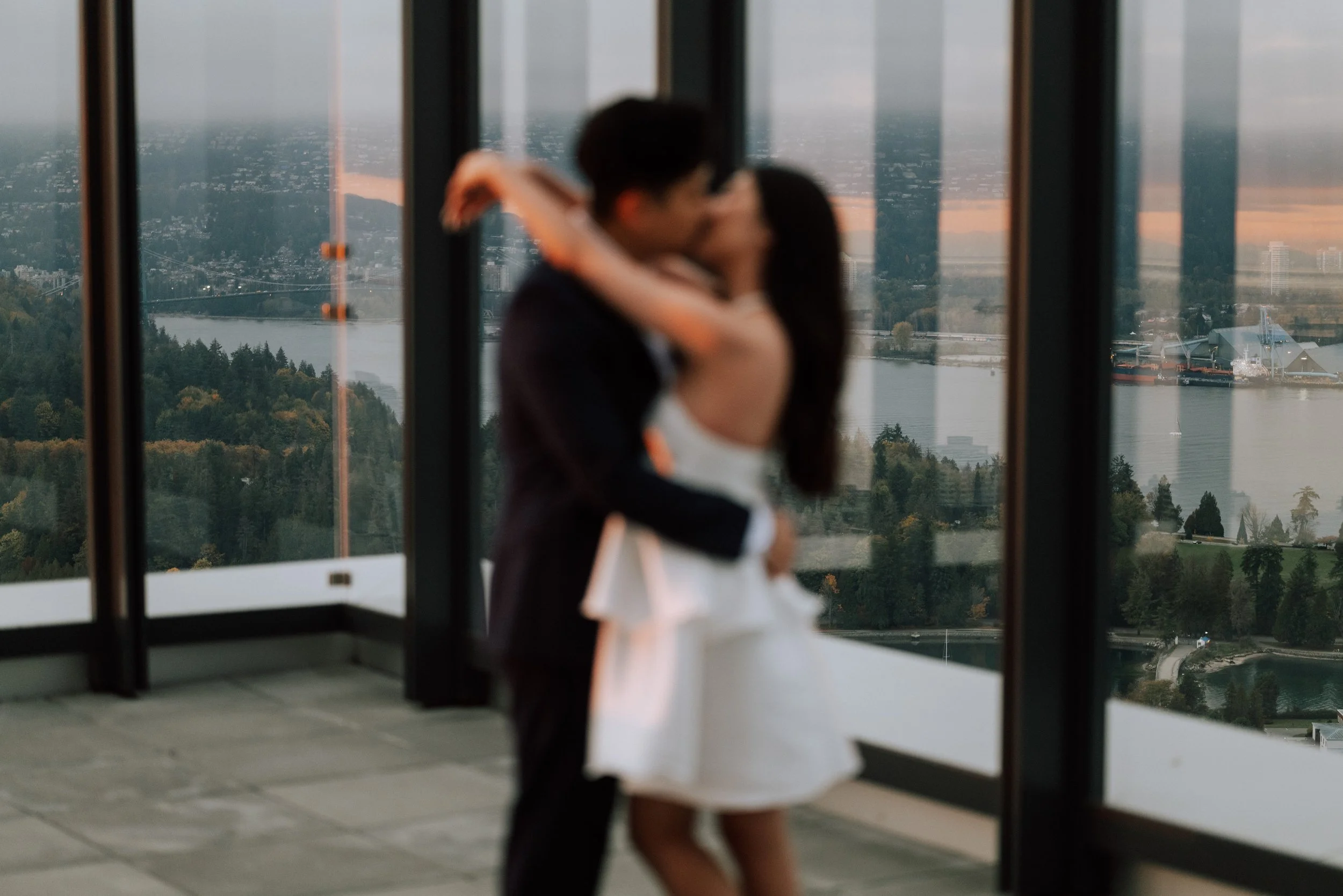 Soft-focus portrait of a couple kissing on a rooftop in Downtown Vancouver.