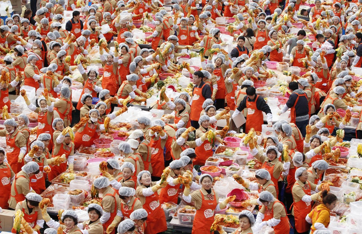 Women pose for the cameras as they make the traditional Korean side dish kimchi, or fermented cabbage, at a charity event at the Seoul City Hall Plaza on November 8, 2011. About 2,000 volunteers made 270 tons of kimchi to give away to needy people during the winter season.
