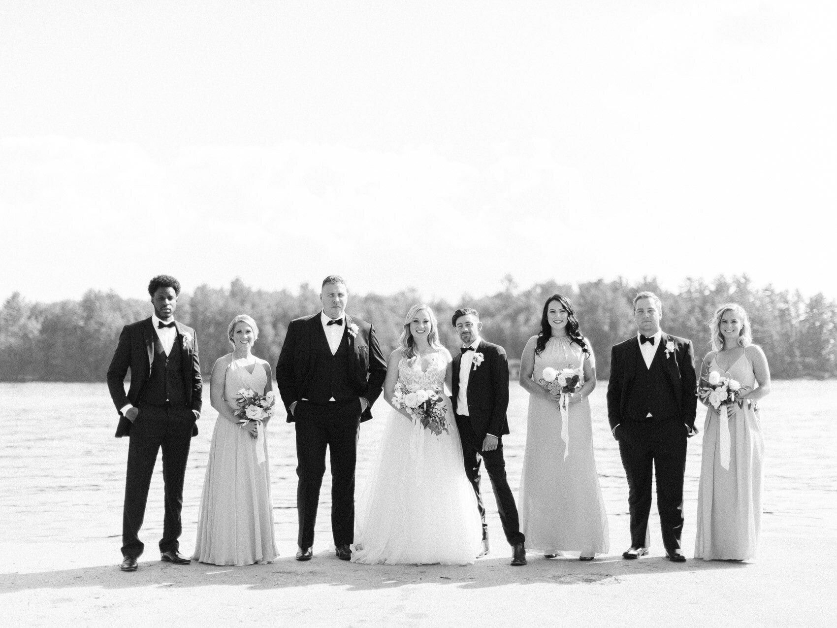 wedding party bridesmaids and groomsmen posing naturally for a candid happy photo at a wedding at windermere house muskoka
