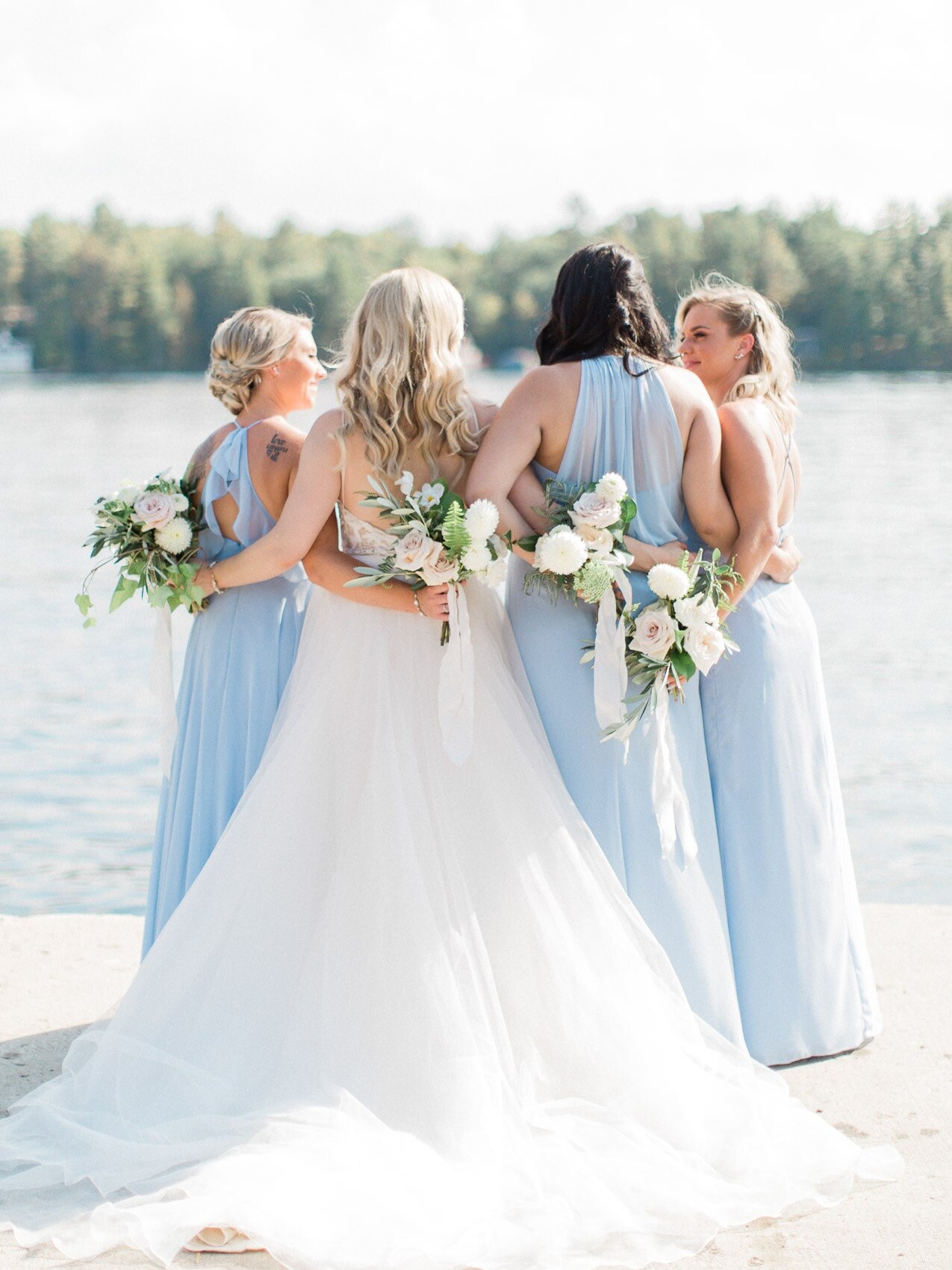 bride and bridesmaids posing naturally for a candid happy photo on their wedding day at windermere house muskoka