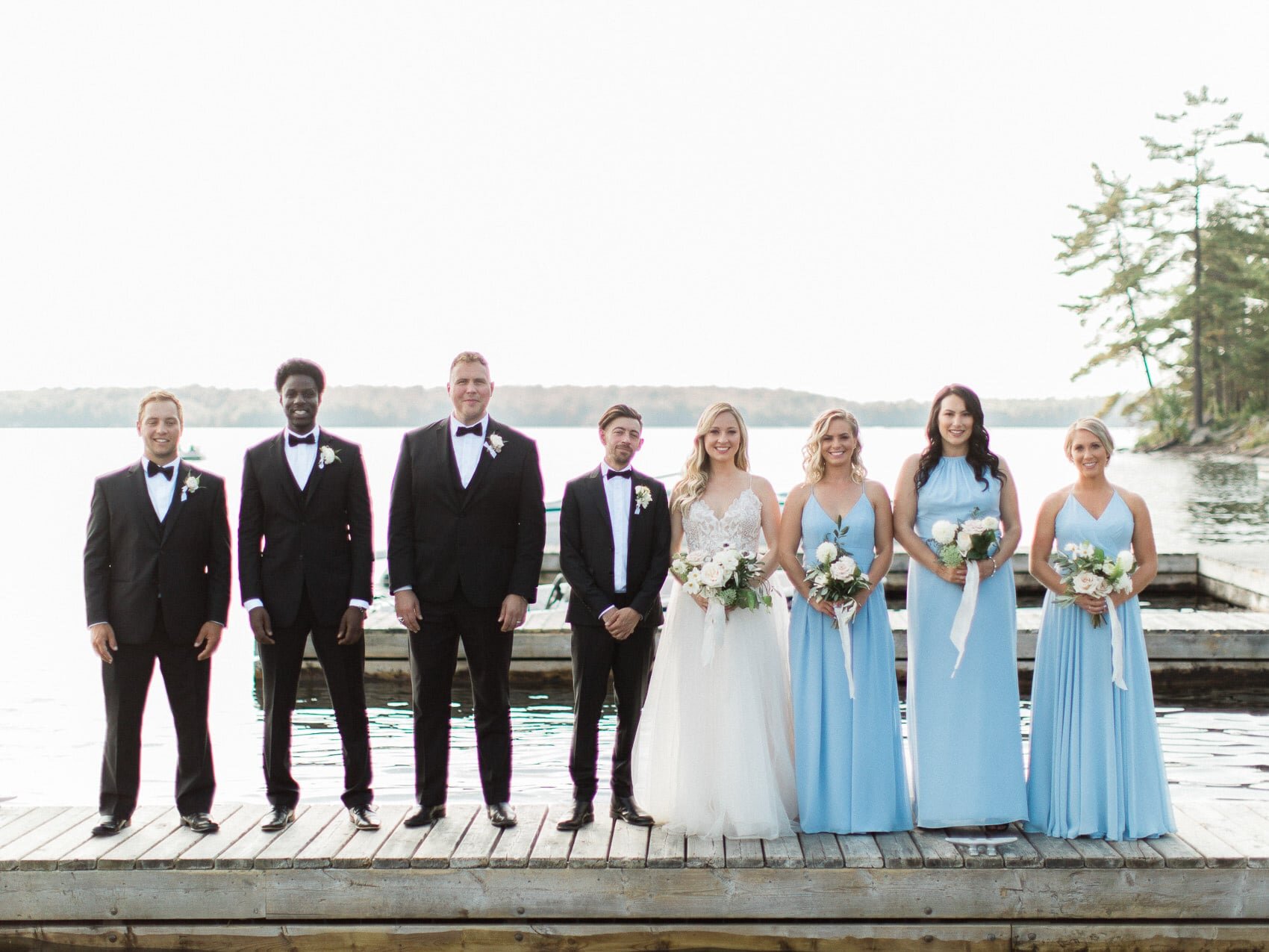 wedding party bridesmaids and groomsmen posing naturally for a candid happy photo at a wedding at windermere house muskoka