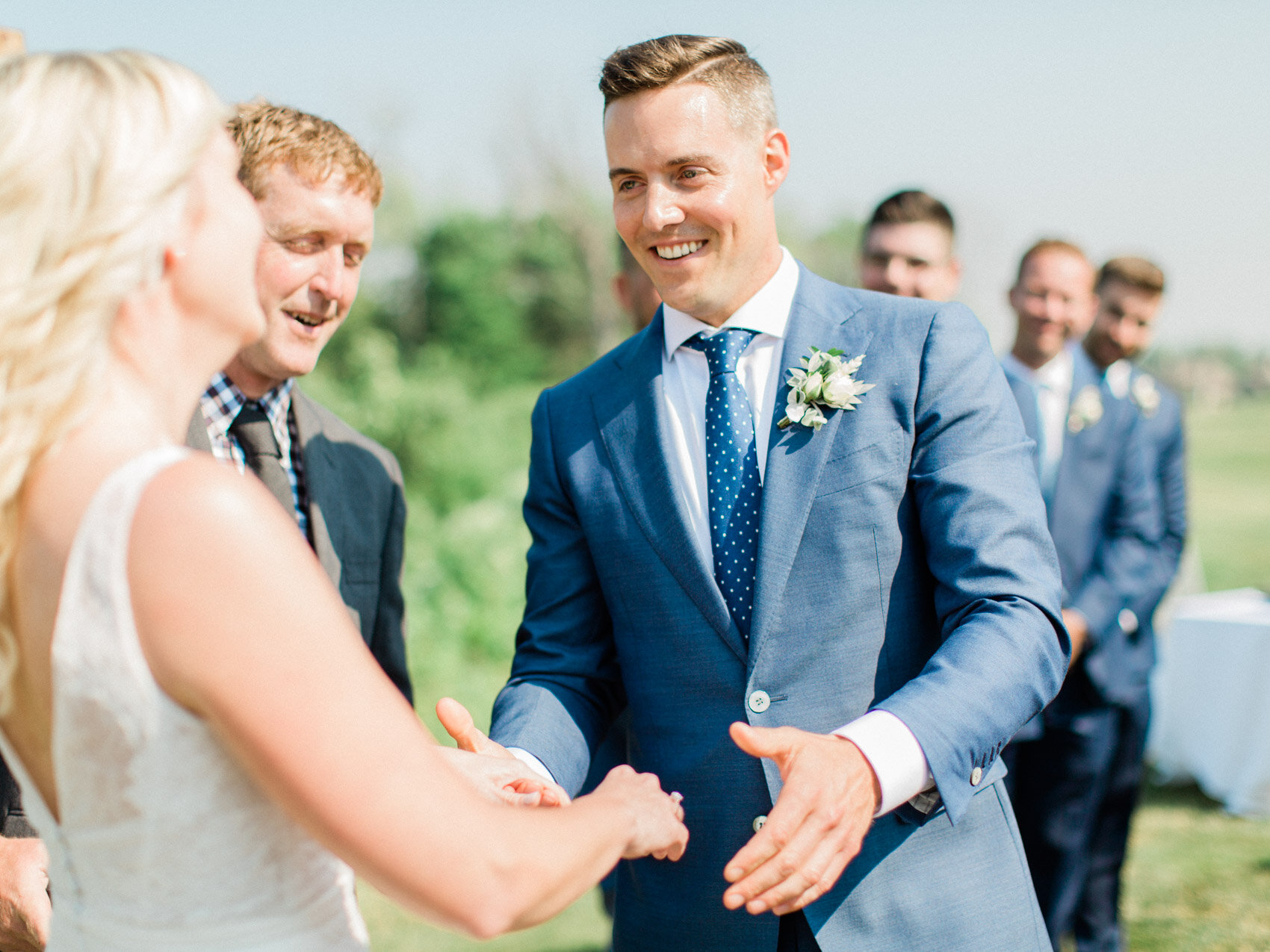 groom smiling at his bride during their outdoor summer wedding ceremony