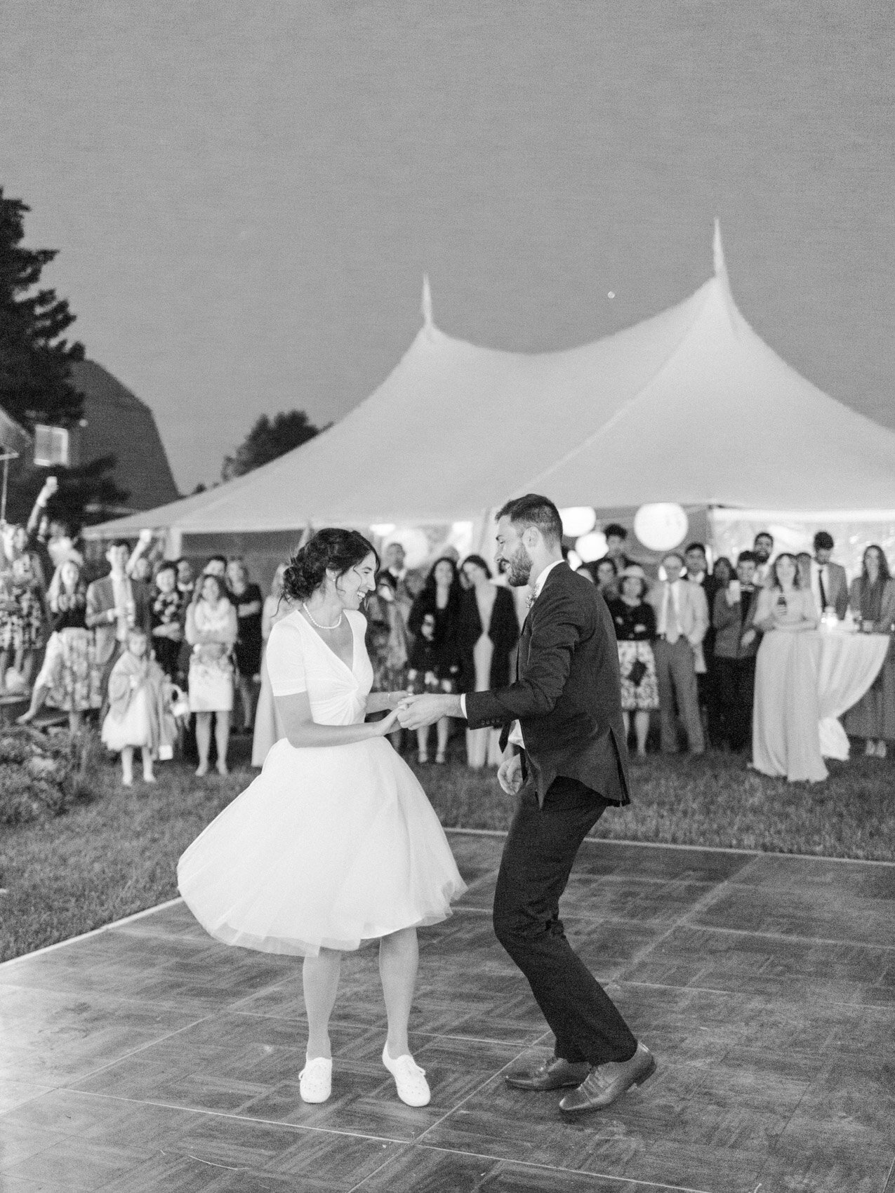 bride and groom swing dancing together at their outdoor summer wedding under the stars