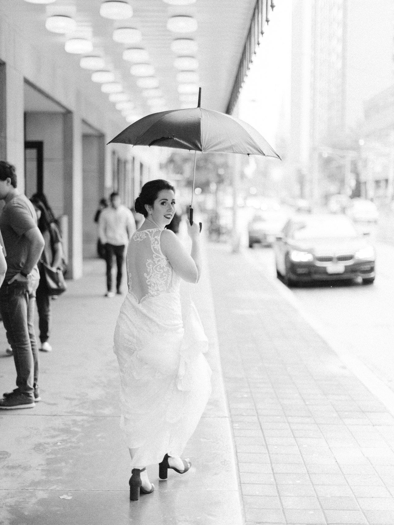 bride carrying an umbrella and walking to her fist look in downtown toronto