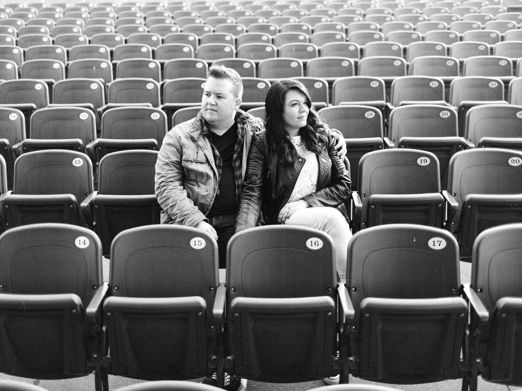 hip urban couple sitting in concert seating together from their toronto engagement session at the bud stage and ontario place park