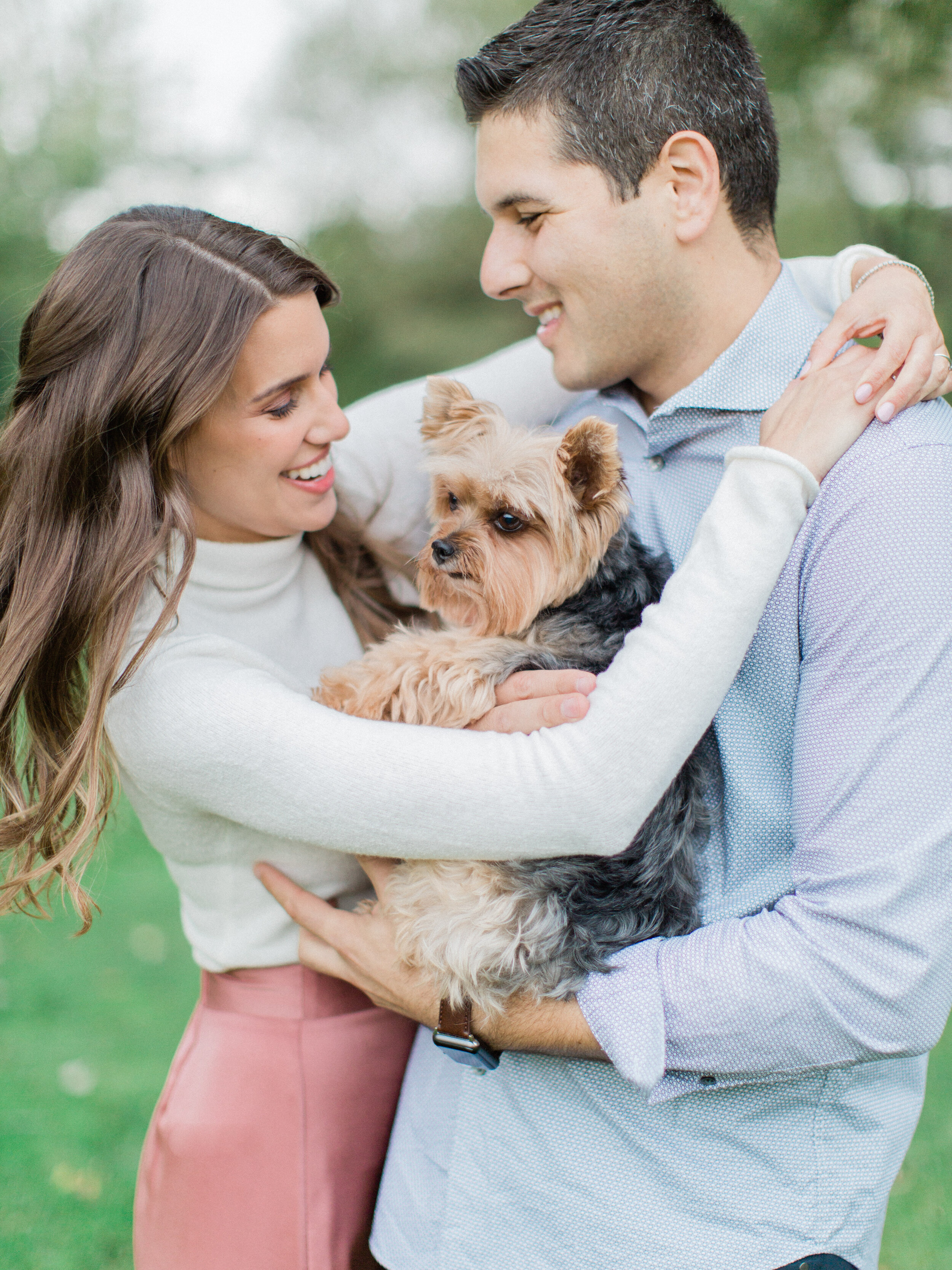 cute candid couple snuggling with their dog in the park during their outdoor summer engagement photography session