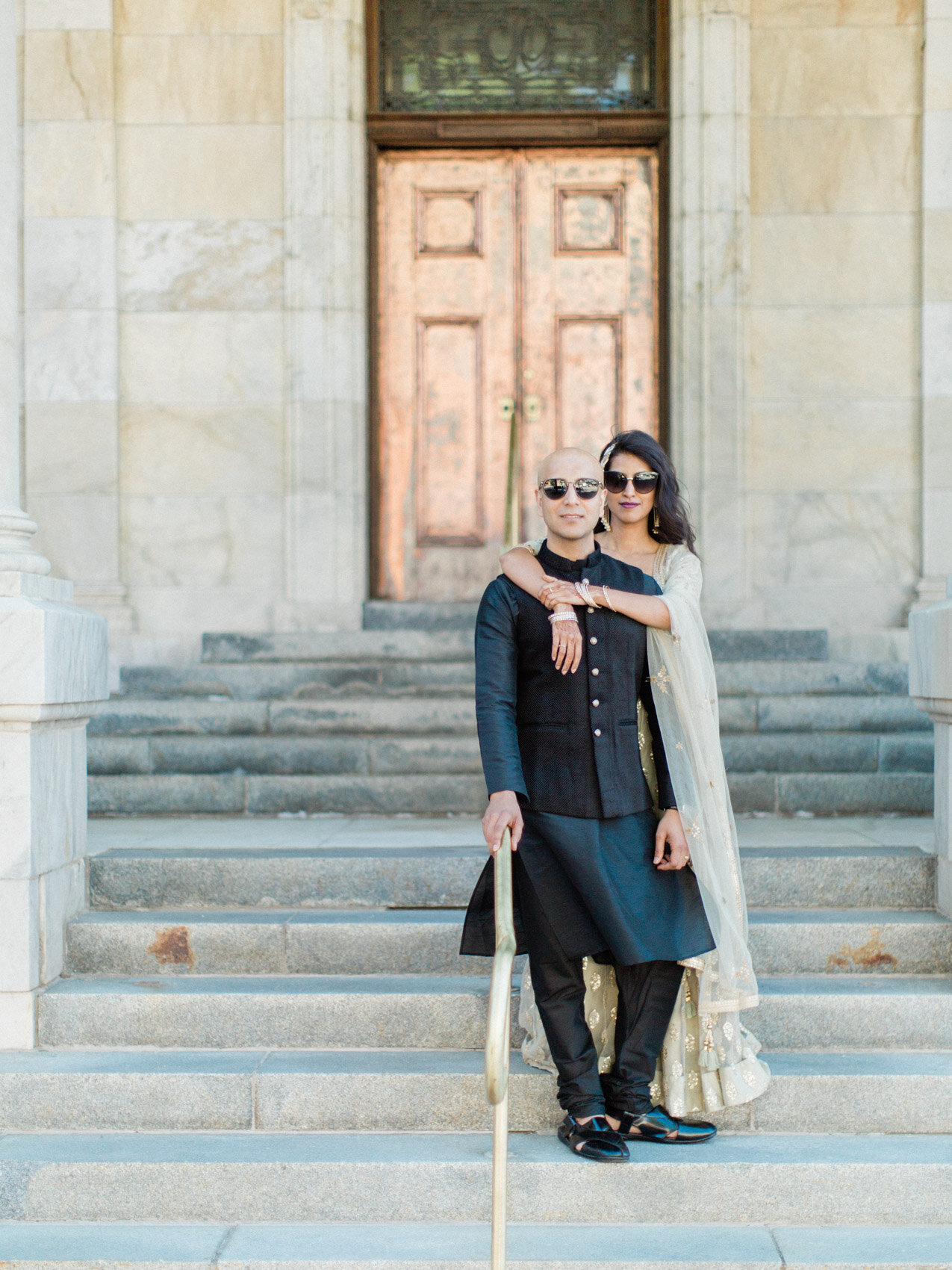 A chic indian couple posing naturally on the court house steps for their engagement photographs