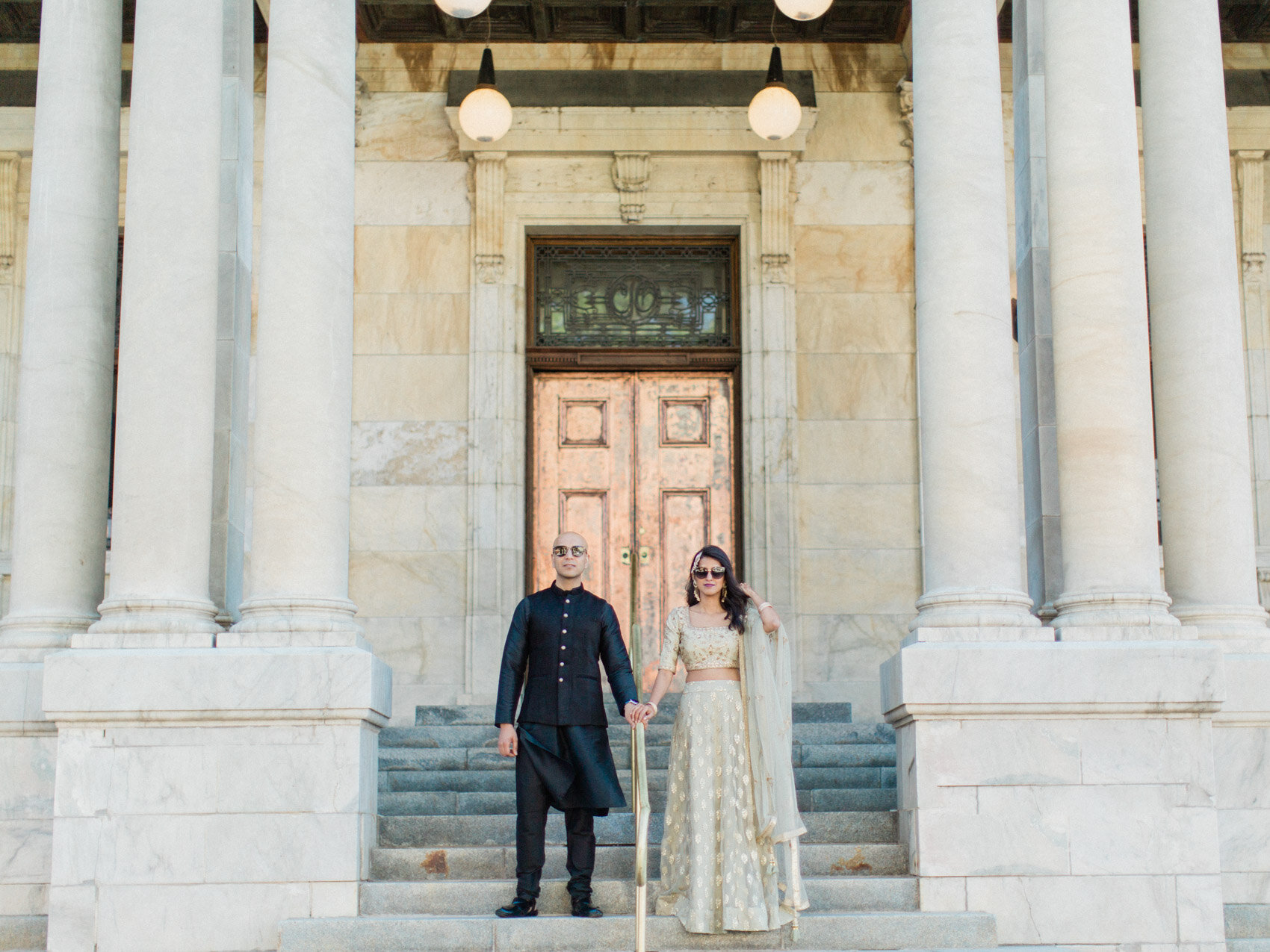 A chic indian couple posing naturally on the court house steps for their engagement photographs