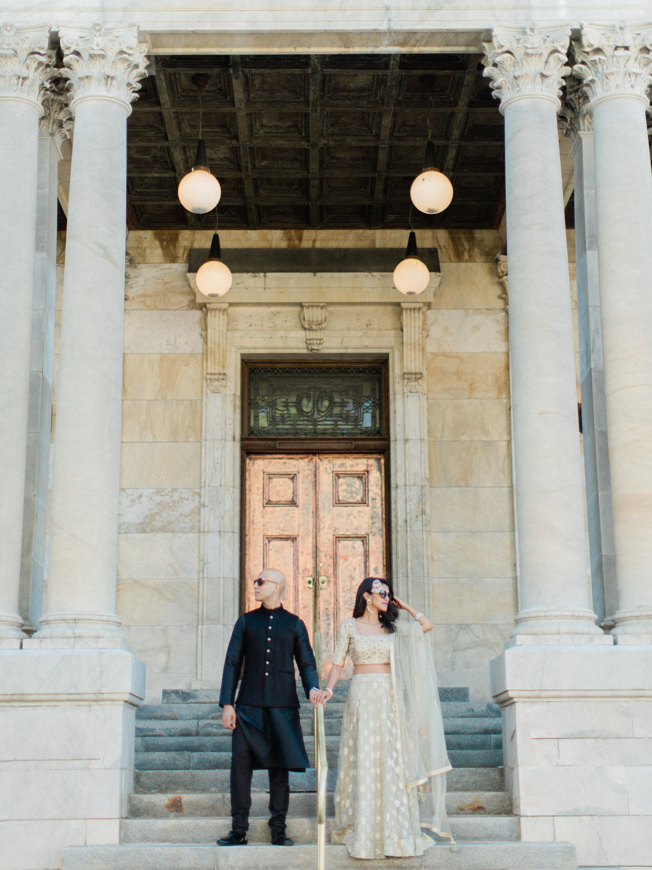 A chic indian couple posing naturally on the court house steps for their engagement photographs
